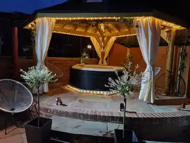 Illuminated hot tub under gazebo.